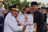 Bupati Agam Andri Warman menyerahkan penghargaan kepada Kepala Disdukcapil Agam Helton. (AMC Agam)
