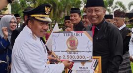 Bupati Agam Andri Warman menyerahkan penghargaan kepada Kepala Disdukcapil Agam Helton. (AMC Agam)
