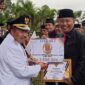 Bupati Agam Andri Warman menyerahkan penghargaan kepada Kepala Disdukcapil Agam Helton. (AMC Agam)