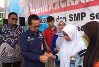 Asisten 1 Setdako Padang Edi Hasymi membagikan TTD kepada siswi.(Diskominfo Padang)