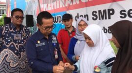 Asisten 1 Setdako Padang Edi Hasymi membagikan TTD kepada siswi.(Diskominfo Padang)