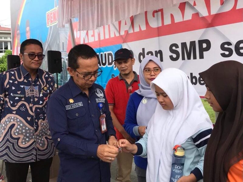 Asisten 1 Setdako Padang Edi Hasymi membagikan TTD kepada siswi.(Diskominfo Padang)