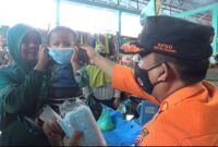 Sekretaris BPBD Kota Padang, Robert Chandra Eka Putra membagikan masker di Pasar Alai, Kamis (5/10/2023). (BPBD Padang)