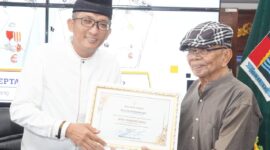 Wali Kota Padang Hendri Septa Dt. Alam Batuah menyerahkan penghargaan kepada Rusli Marzuki Saria, Minggu (5/5/2024). (Foto: Prokopim Padang)