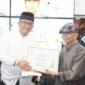 Wali Kota Padang Hendri Septa Dt. Alam Batuah menyerahkan penghargaan kepada Rusli Marzuki Saria, Minggu (5/5/2024). (Foto: Prokopim Padang)