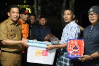Pj Wali Kota, Sonny Budaya Putra menyerahkan bantuan kepada warga yang terdampak banjir bandang lahar dingin, Selasa (14/5/2024) malam. (Foto: Kominfo Padang Panjang)