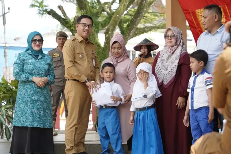 Bupati Solsel Khairunas menyerahkan secara simbolis seragam sekolah gratis kepada siswa. (Foto: Humas Pemkab Solsel)