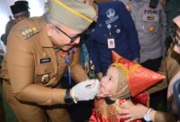 Pj Wali Kota Padang Andree Algamar secara simbolis memberikan imunisasi kepada salah seorang anak. (Foto: Prokopim Padang)