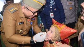 Pj Wali Kota Padang Andree Algamar secara simbolis memberikan imunisasi kepada salah seorang anak. (Foto: Prokopim Padang)