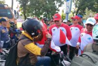 Pj Wali Kota Padang Andree Algamar membagikan bendera merah putih kepada pengguna jalan di depan Kantor Balai Kota Padang, Rabu (31/7/2024). 