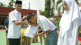 Wakil Bupati Solsel Yulian Efi menyerahkan seragam sekolah kepada siswa di SMAN 5 Solok Selatan. (Foto: Pemkab Solsel)