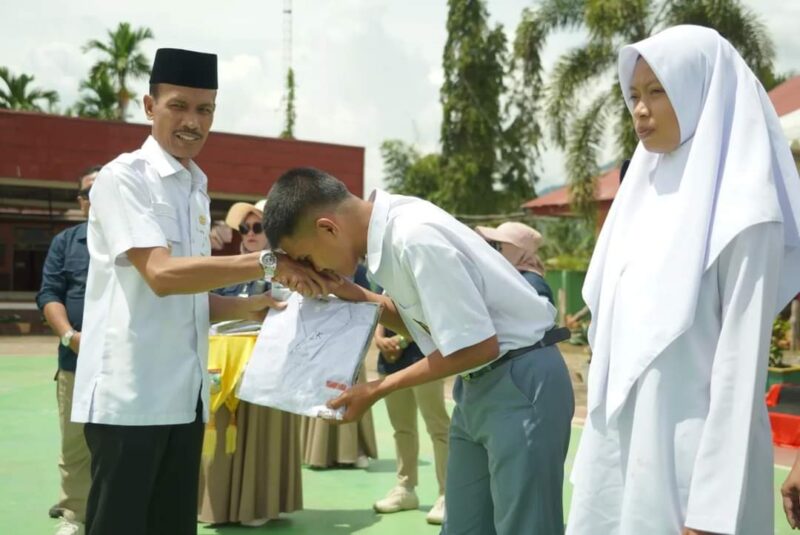 Wakil Bupati Solsel Yulian Efi menyerahkan seragam sekolah kepada siswa di SMAN 5 Solok Selatan. (Foto: Pemkab Solsel)