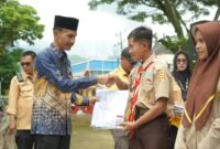 Wakil Bupati Solok Selatan, Yulian Efi menyerahkan seragam sekolah kepada siswa. (Foto: Pemkab Solsel)