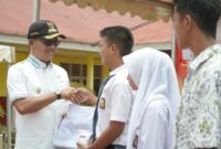 Bupati Solsel Khairunas menyerahkan seragam sekolah kepada siswa. (Foto: Prokopim Solsel)