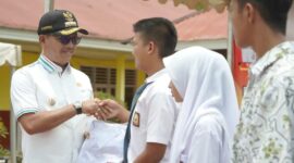 Bupati Solsel Khairunas menyerahkan seragam sekolah kepada siswa. (Foto: Prokopim Solsel)