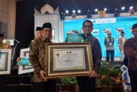 Kepala Biro Kesra Setdaprov Sumbar, Al Amin menerima penghargaan dari Dirjen Bimas Islam Kemenag RI, Kamaruddin Amin. (Foto: ADPSB)