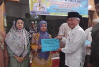 Staf Ahli Bidang Kemasyarakatan dan SDM, Syahrial Kamat menyerahkan dana operasional RT/RW di Masjid Raya Balai Gadang Koto Tangah, Jumat (25/10/2024). (Foto: Diskominfo Padang)