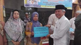 Staf Ahli Bidang Kemasyarakatan dan SDM, Syahrial Kamat menyerahkan dana operasional RT/RW di Masjid Raya Balai Gadang Koto Tangah, Jumat (25/10/2024). (Foto: Diskominfo Padang)