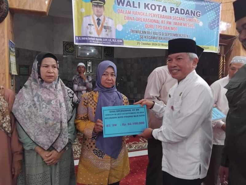 Staf Ahli Bidang Kemasyarakatan dan SDM, Syahrial Kamat menyerahkan dana operasional RT/RW di Masjid Raya Balai Gadang Koto Tangah, Jumat (25/10/2024). (Foto: Diskominfo Padang)