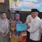Staf Ahli Bidang Kemasyarakatan dan SDM, Syahrial Kamat menyerahkan dana operasional RT/RW di Masjid Raya Balai Gadang Koto Tangah, Jumat (25/10/2024). (Foto: Diskominfo Padang)