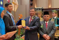 Kepala BPSDMI Kemenperin RI Masrokhan didampingi Kepala SMK SMAK Padang Nasir menyerahkan penghargaan kepada siswa teladan pada wisuda angkatan ke-56, Rabu (16/10/2024).  (Foto: SMK SMAK Padang)