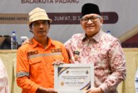 Pj Wali Kota Padang Andree Algamar menyerahkan reward umrah kepada Eferoni Lase. (Foto: Prokopim Padang)