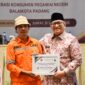 Pj Wali Kota Padang Andree Algamar menyerahkan reward umrah kepada Eferoni Lase. (Foto: Prokopim Padang)