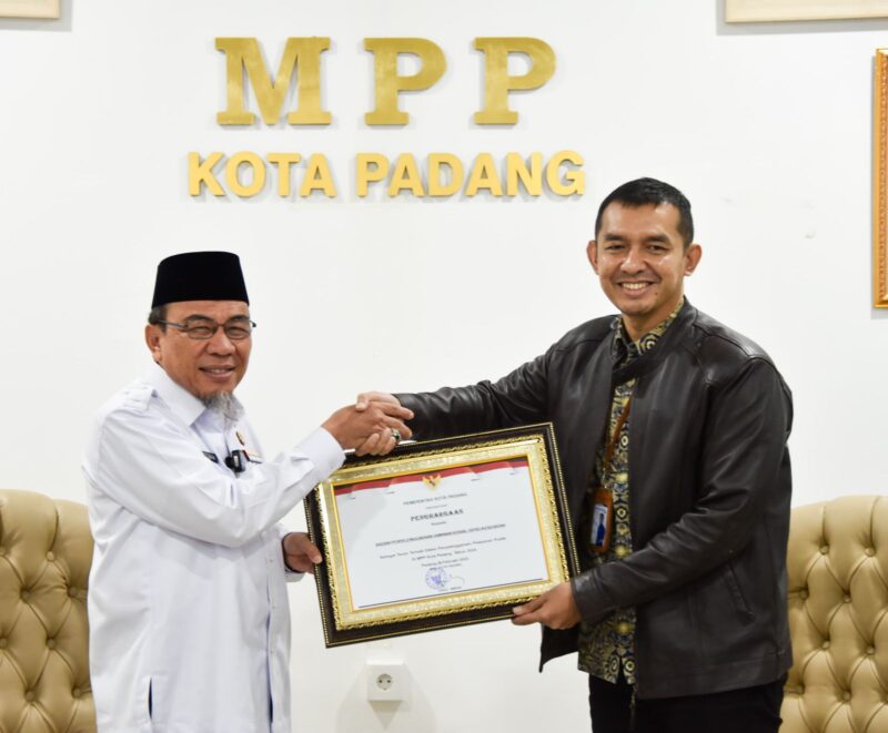 Wawako Padang Maigus Nasir menyerahkan penghargaan Kepala Kantor BPJS Kesehatan Cabang Padang Fauzi Lukman Nurdiansyah, di Gedung MPP Padang Lantai 4 Plaza Andalas, Rabu (26/2). (Foto: Prokopim Padang)