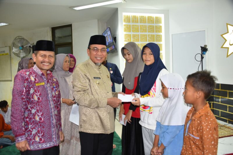Wakil Wali Kota Padang, Maigus Nasir menyerahkan santunan kepada anak yatim di Masjid Ukhuwah, Komplek Perkantoran Balai Kota Padang, Aie Pacah, pada Jumat (21/3/2025). (Foto: Prokopim Padang)