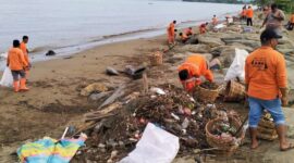 Pasukan Oranye dari DLH Kota Padang bekerja membersihkan tumpukan sampah yang memenuhi Pantai Padang. (Foto: FB Diskominfo Padang)