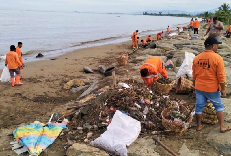 Pasukan Oranye dari DLH Kota Padang bekerja membersihkan tumpukan sampah yang memenuhi Pantai Padang. (Foto: FB Diskominfo Padang)