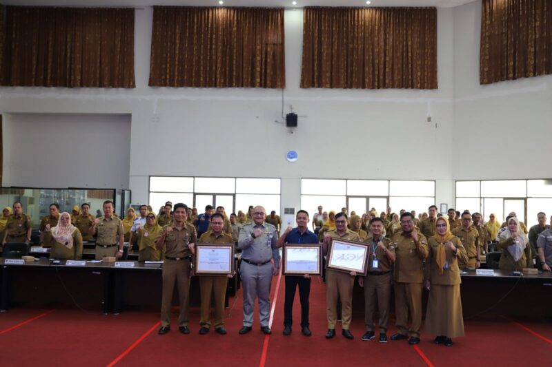 Sekda Kota Padang Andree Algamar memberikan penghargaan kepada tiga perangkat daerah terbaik dalam penyampaian laporan dan capaian realisasi fisik dan keuangan tahun 2024, Selasa (29/4/2025). (Foto: Prokopim Padang)