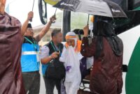Petugas sigap memayungi Jemaah haji di tengah hujan deras. (Foto: Humas Kemenag Sumbar)