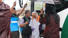 Petugas sigap memayungi Jemaah haji di tengah hujan deras. (Foto: Humas Kemenag Sumbar)