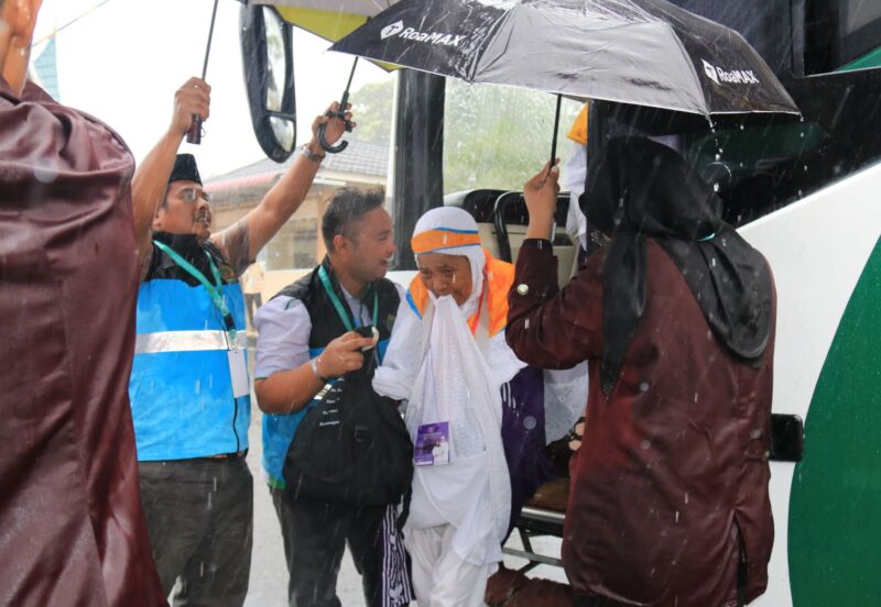 Petugas sigap memayungi Jemaah haji di tengah hujan deras. (Foto: Humas Kemenag Sumbar)