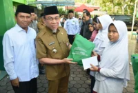 Wakil Wali Kota Padang Maigus Nasir didampingi Kakan Kemenag Edy Oktafiandi menyerahkan bantuan kepada penerima manfaat pada Festival Muharram 1447 H, Selasa (8/7/2025). (Foto: Prokopim Padang)