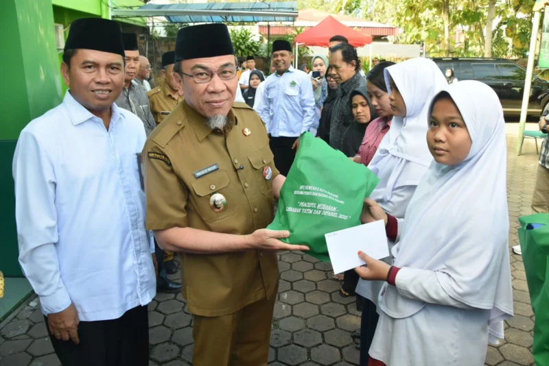 Wakil Wali Kota Padang Maigus Nasir didampingi Kakan Kemenag Edy Oktafiandi menyerahkan bantuan kepada penerima manfaat pada Festival Muharram 1447 H, Selasa (8/7/2025). (Foto: Prokopim Padang)