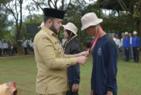Wali Kota Padang Fadly mengalungkan tanda peserta DIKSISTA MAN 3 Padang di Bumi Perkemahan Sungrilla, Kecamatan Koto Tangah, Senin (21/7/2025). (Foto: Prokopim Padang)