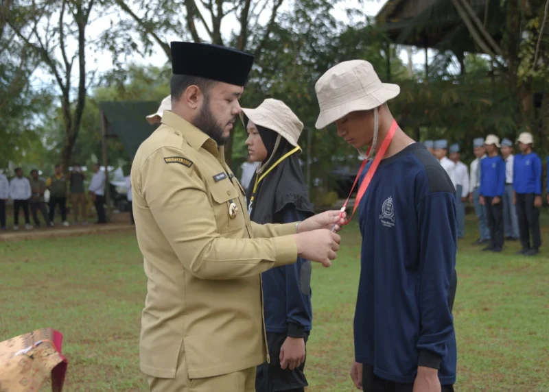 Wali Kota Padang Fadly mengalungkan tanda peserta DIKSISTA MAN 3 Padang di Bumi Perkemahan Sungrilla, Kecamatan Koto Tangah, Senin (21/7/2025). (Foto: Prokopim Padang)