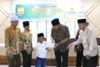 Wali Kota Pariaman, Yota Balad menyerahkan zakat kepada mustahik di Balairung Rumah Dinas Wali Kota, Jumat (18/7/2025). (Foto: Kominfo Pariaman)