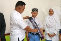 
Ketua Bawaslu Pessel, Afriki Musmaidi memasangkan selempang kepada Aliffran Gunawan dan Arini Soleha saat dinobatkan sebagai Duta Informasi PPID. (Foto: Dok Humas Bawaslu)