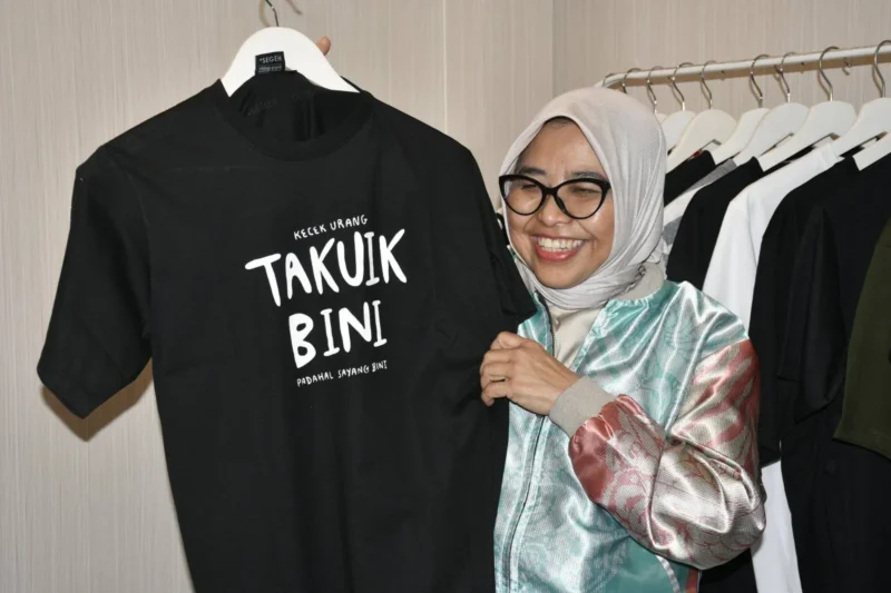 Sekretaris Menteri Ekraf/Bekraf RI, Dessy Ruhati memborong kaos hitam bertuliskan “Takuik Bini” yang terpajang di Galeri Dekranasda Padang, Sabtu (9/8/2025). (Foto: Diskominfo Padang)