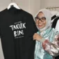 Sekretaris Menteri Ekraf/Bekraf RI, Dessy Ruhati memborong kaos hitam bertuliskan “Takuik Bini” yang terpajang di Galeri Dekranasda Padang, Sabtu (9/8/2025). (Foto: Diskominfo Padang)