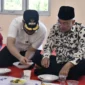 Presiden DMDI, Tun Seri Setia Dr. H. Mohd. Ali Bin Mohd. Rustam mencicipi rendang yang dimasak di Sentra Rendang, Sabtu (9/8/2025). (Foto: Diskominfo Padang) 