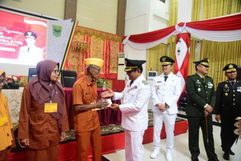 Bupati Padang Pariaman Dr. H. John Kenedy Azis menyerahkan tali asih kepada veteran yang tergabung dalam LVRI Padang Pariaman, Minggu (17/8/2025). (Foto: Kominfo Padang Pariaman) 