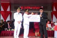 Bupati Padang Pariaman John Kenedy Azis menerima dividen tahun buku 2024 dari Kepala Bank Nagari Cabang Lubuk Alung, Afrizon, SE, Minggu (17/8/2025). (Foto: Kominfo Padang Pariaman)