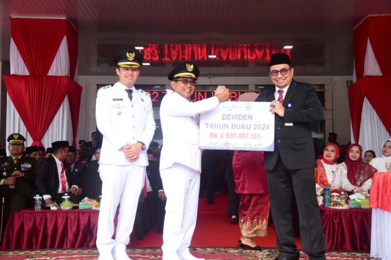 Bupati Padang Pariaman John Kenedy Azis menerima dividen tahun buku 2024 dari Kepala Bank Nagari Cabang Lubuk Alung, Afrizon, SE, Minggu (17/8/2025). (Foto: Kominfo Padang Pariaman)
