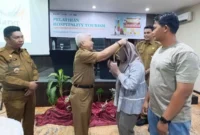 Staf Ahli Wali Kota Padang Bidang SDM dan Kemasyarakatan, Syahrial Kamat memasangkan kokarde kepada peserta pelatihan. (Foto: Diskominfo Padang)
