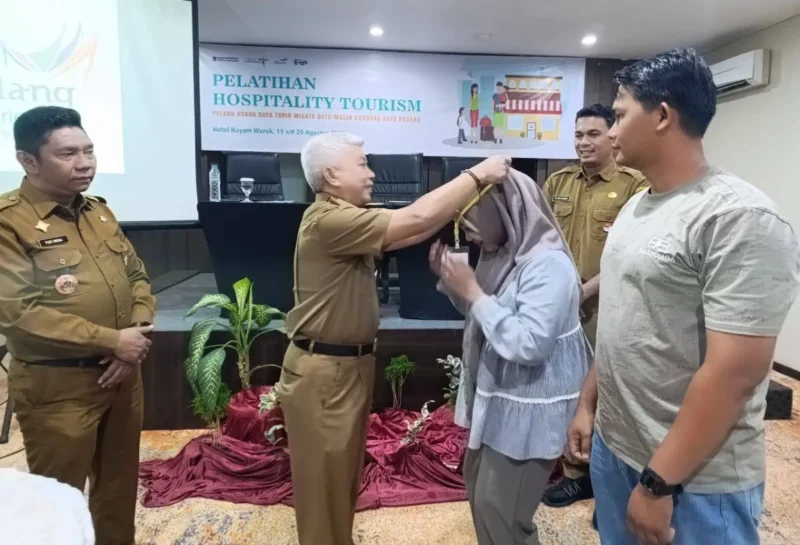 Staf Ahli Wali Kota Padang Bidang SDM dan Kemasyarakatan, Syahrial Kamat memasangkan kokarde kepada peserta pelatihan. (Foto: Diskominfo Padang)