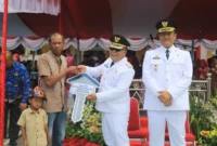 Bupati Pasbar Yulianto menyerahkan bantuan CSR perusahaan sawit kepada keluarga penerima manfaat, Minggu (17/8/2025). (Foto: Diskominfo Pasbar)